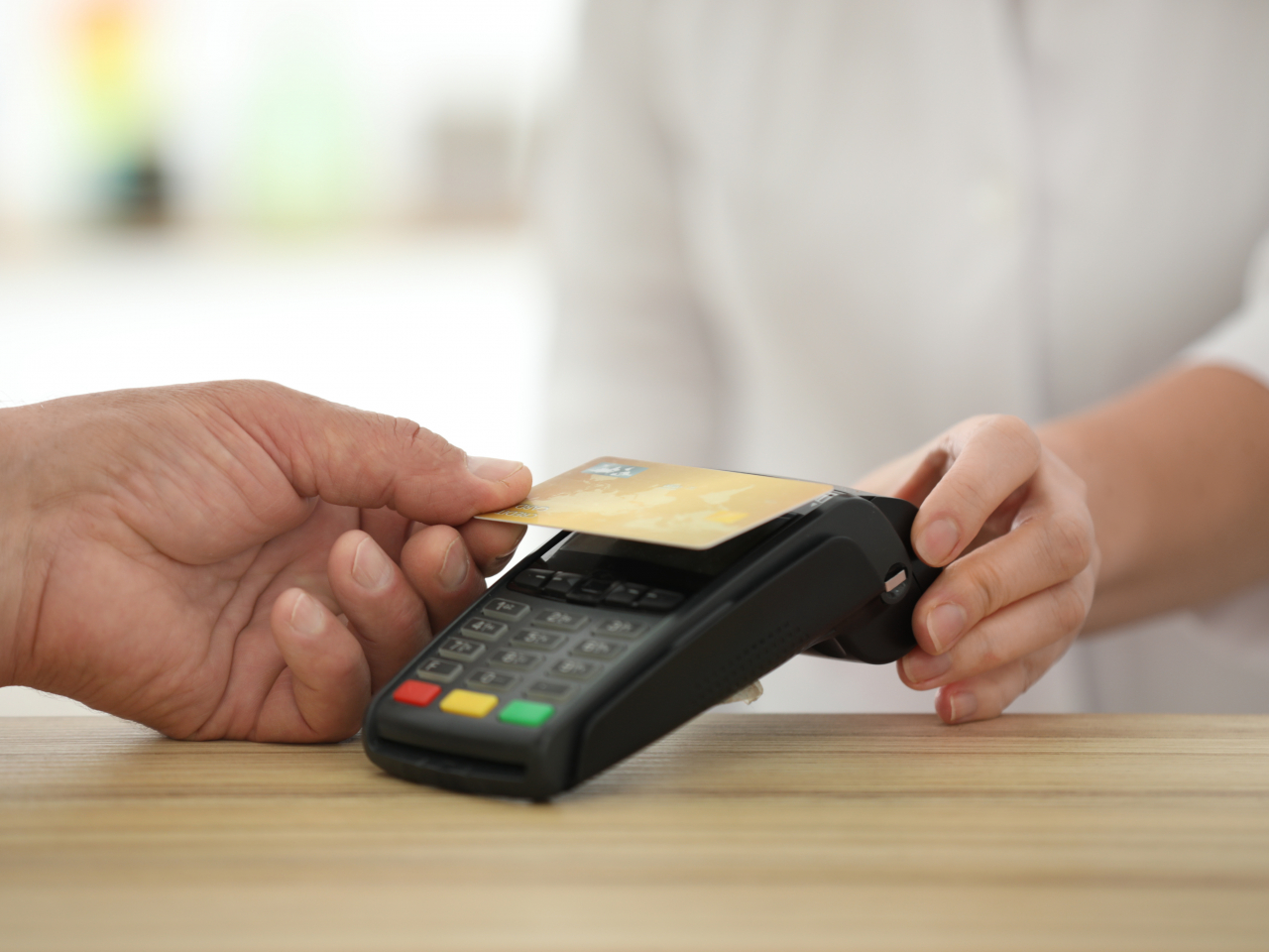 Jemand hält seine Geldkarte kontaktlos an ein Bezahlgerät
