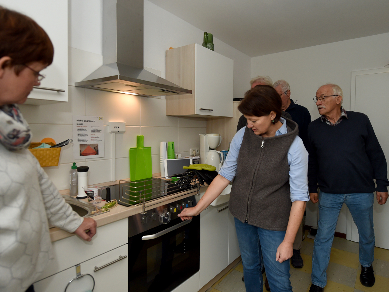 Frau zeigt einer Gruppe Herdabschaltung