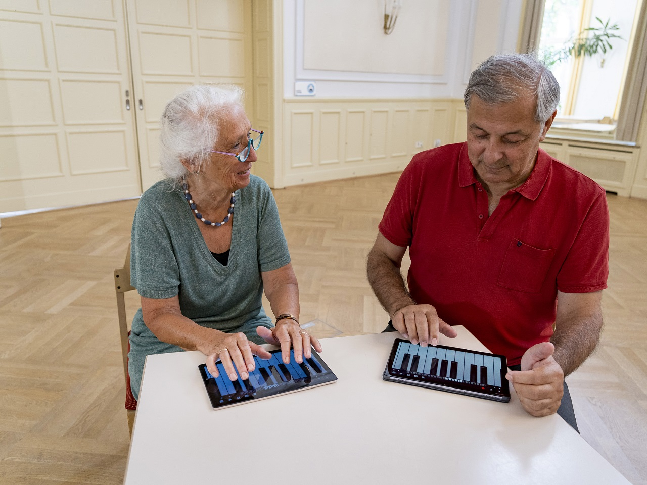 Ein Mann und eine Frau spielen auf einem Tablet Klavier