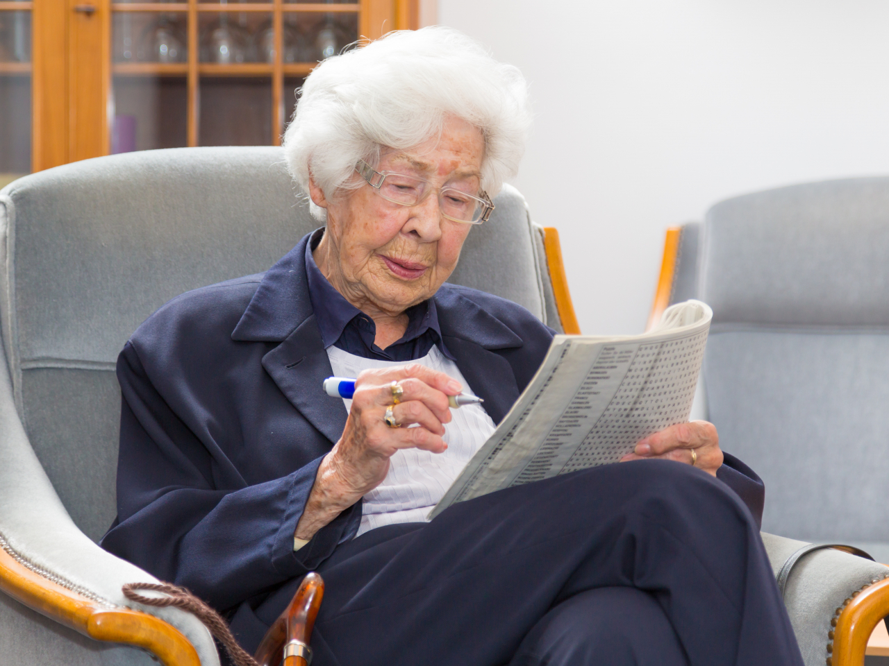 Ältere Frau löst Kreuzworträtsel im Sessel